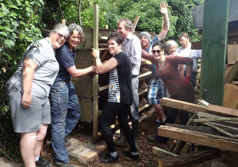 Team celebrating after having moved a wooden storage shelter together 