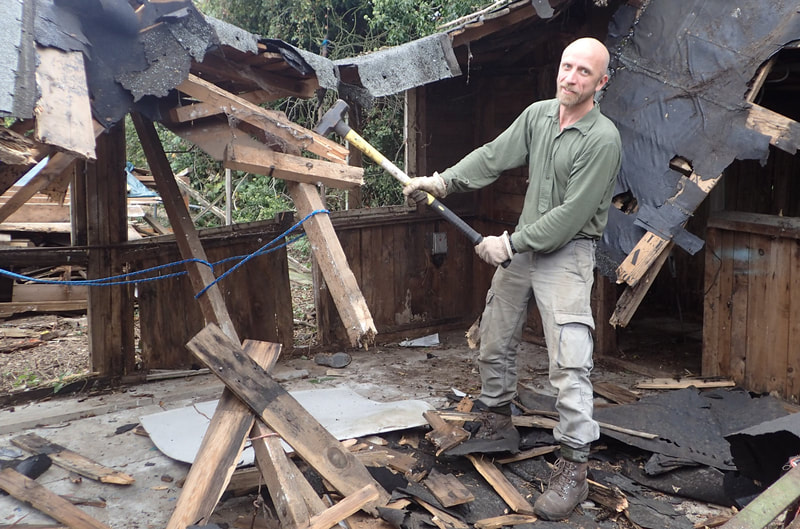 Man using a sledgehammer to knock down old shed
